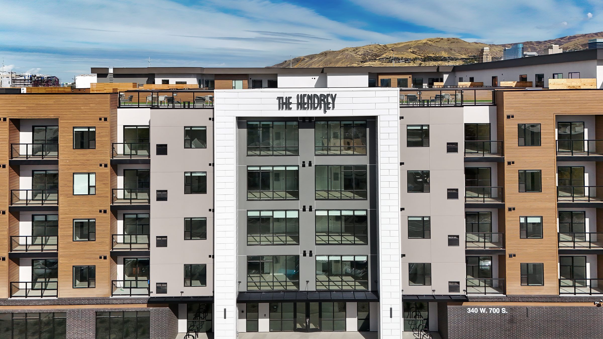 The Hendry apartments exterior building with balconies, large windows, and mountains in the background.