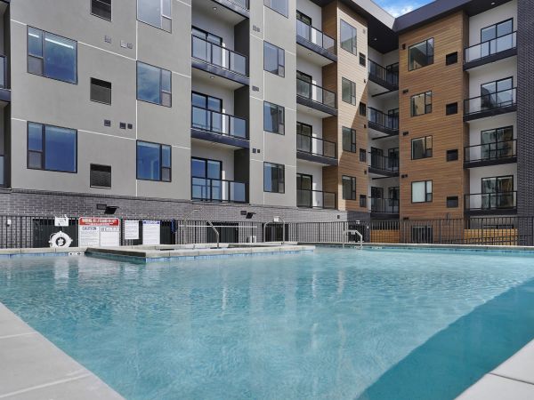 The Hendrey apartment building with balconies overlooking a clear outdoor swimming pool on a sunny day.