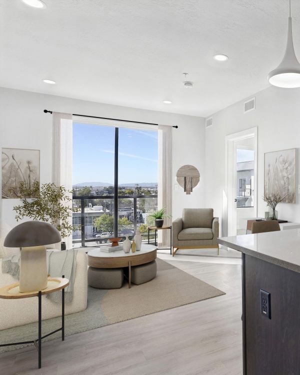 Modern, bright apartment with island kitchen, cozy living area, large windows, and neutral decor at The Hendrey.