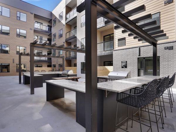 The Hendrey apartment courtyard with outdoor kitchen, grills, bar seating, and surrounding balconies.