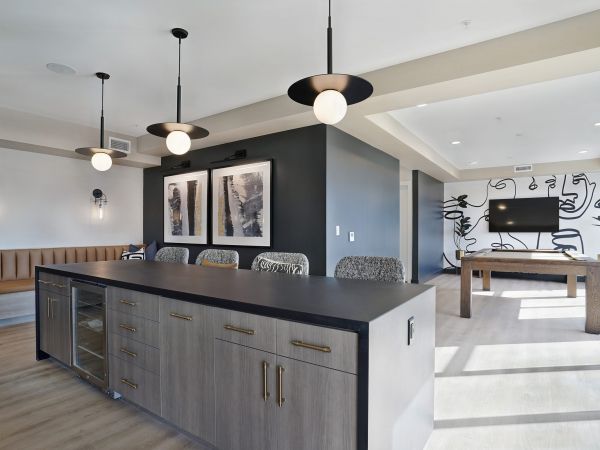 Modern lounge with a large island, pendant lights, bench seating, wall art, and a game table in back at The Hendrey.